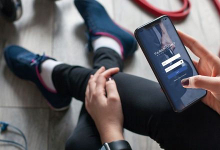 woman surrounded by workout tools looking at our app on her phone