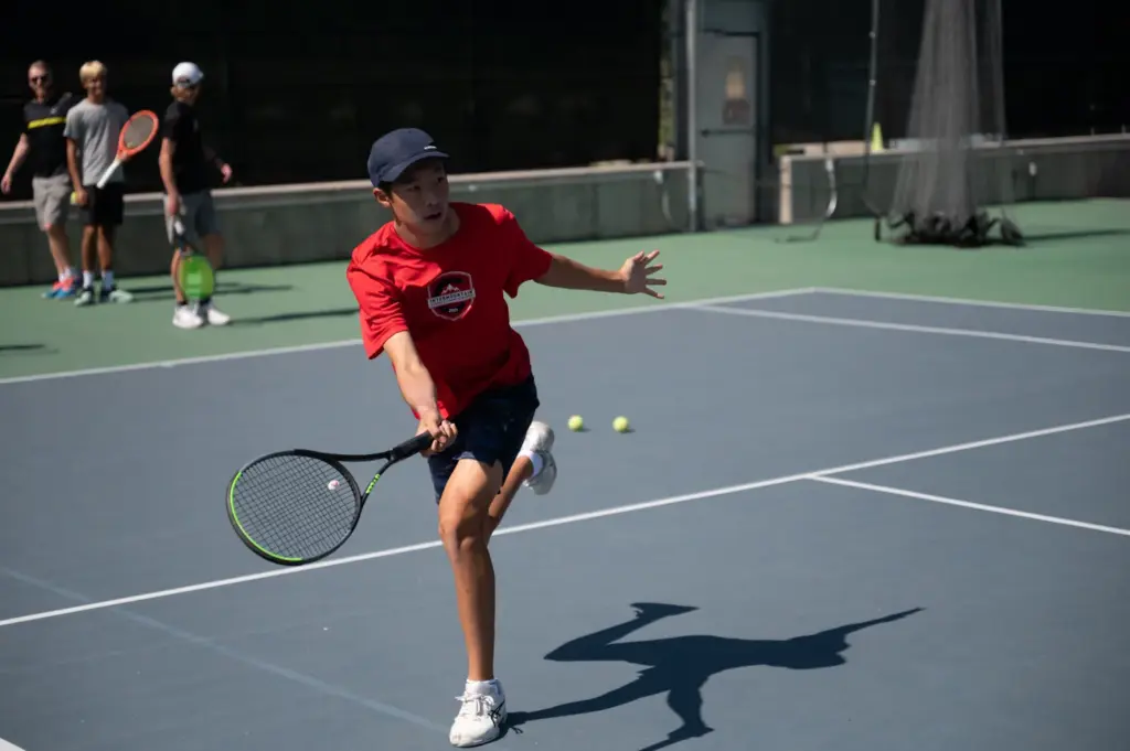 Junior player hitting a one-handed backhand on the indoor courts