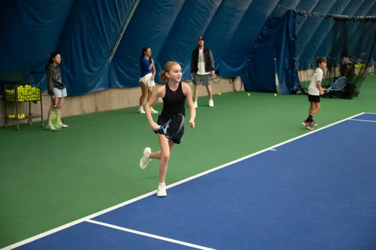 Junior tennis player running to the ball during high performance training