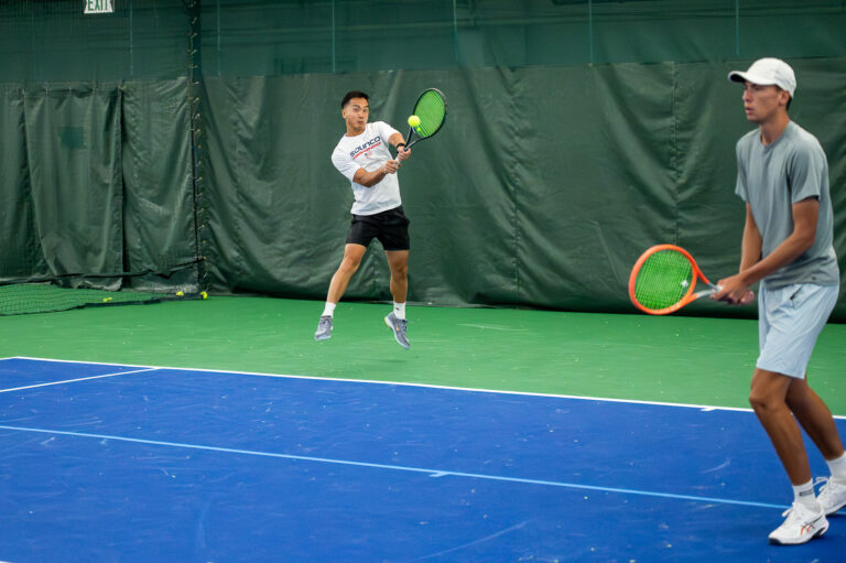 Two players rallying in an adult tennis drill