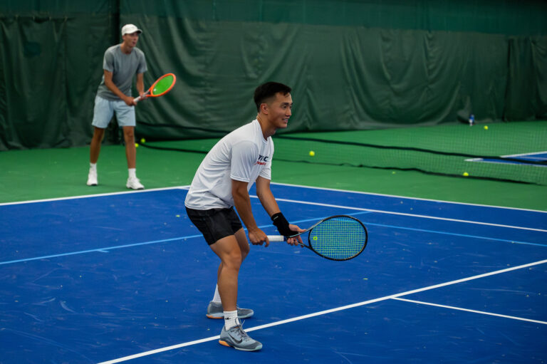 Adult players in ready position during a tennis drill