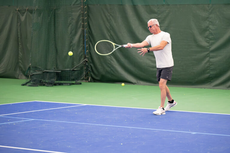 Adult player hitting a forehand on an indoor court