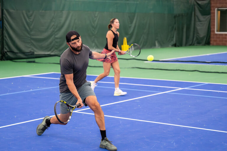 Adult tennis players at the net during a doubles drill