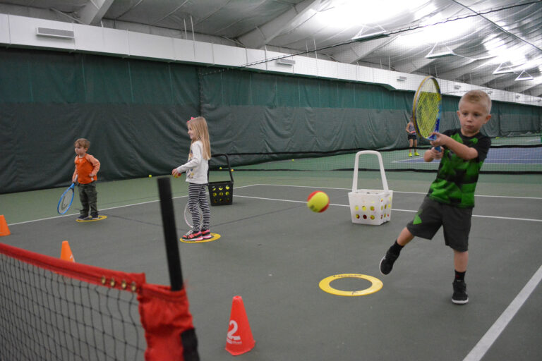 Kids in a Red Ball tennis class with cones and targets